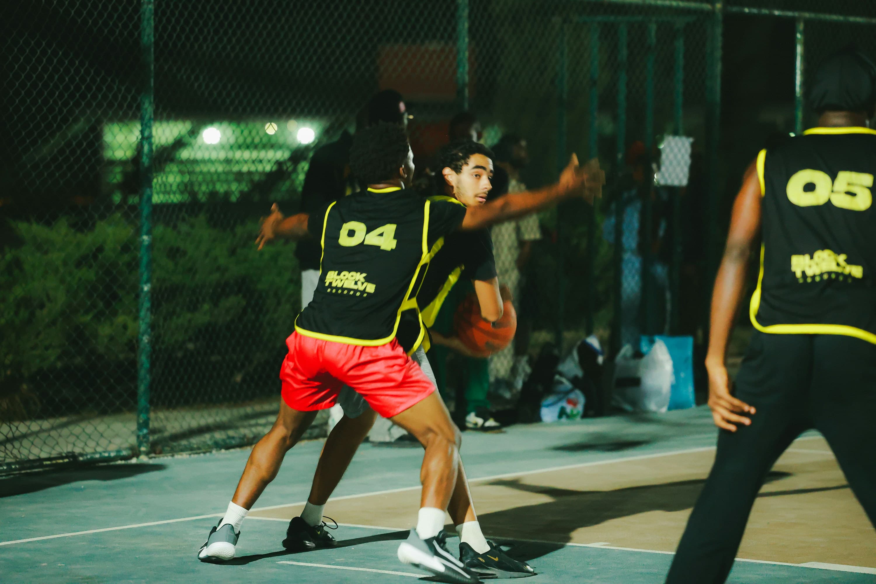 Two competitive pickup basketball players defending under the lights